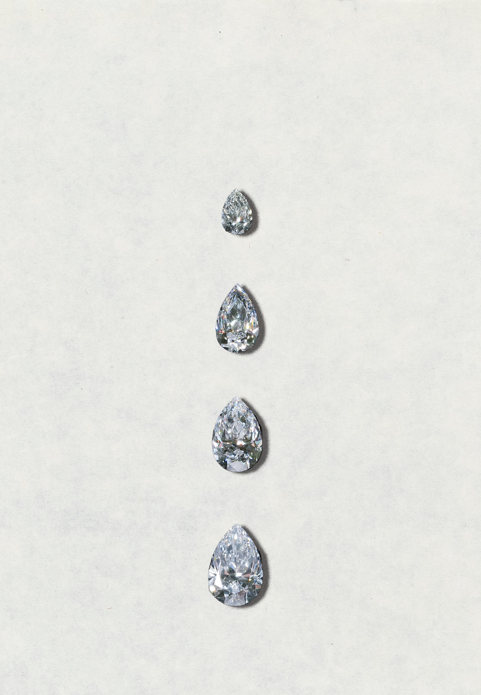 Five pear-shaped diamonds of varying sizes on a light gray background