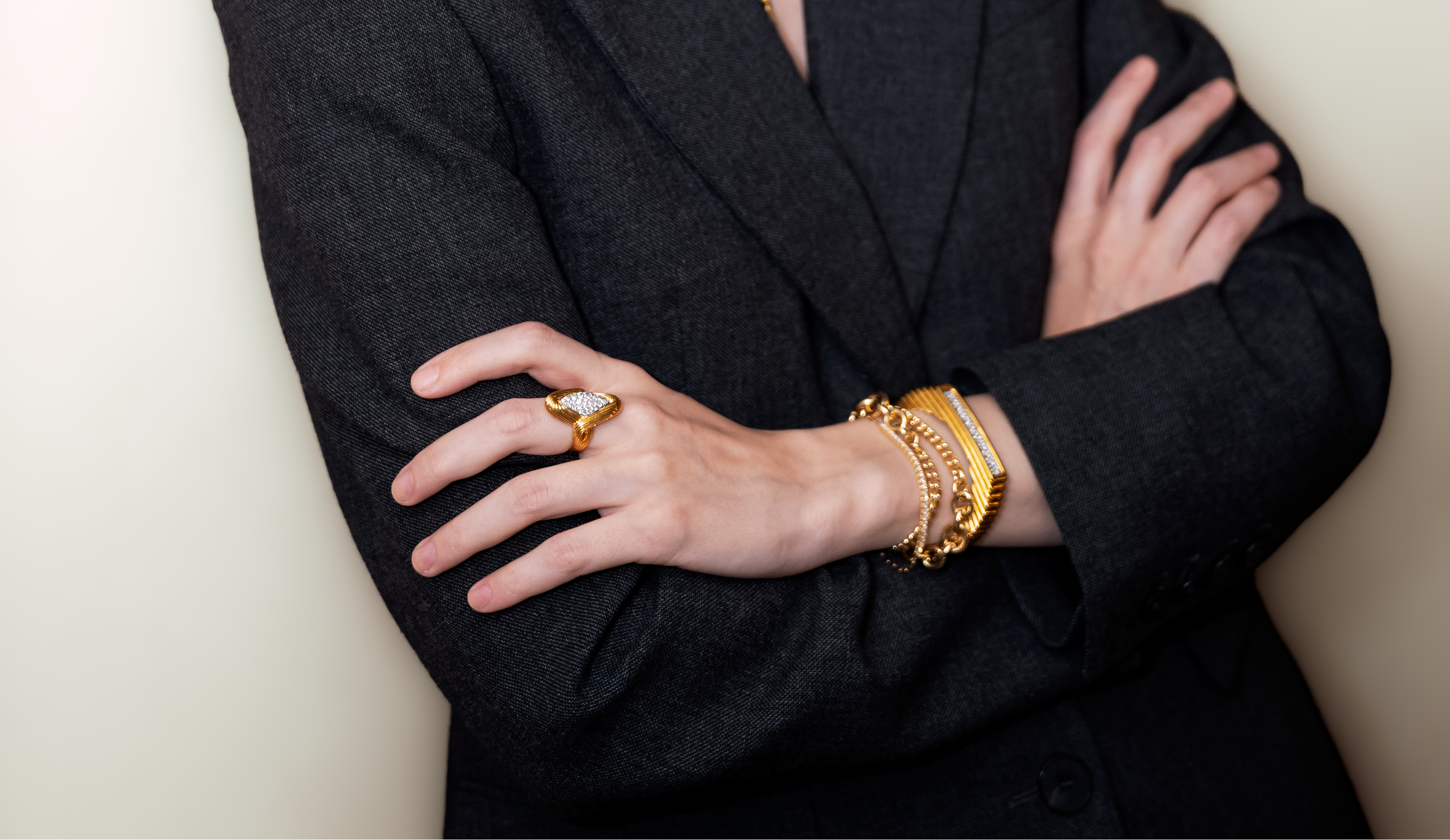 Woman wearing 18K gold diamond bracelet bangle in a black wool suit